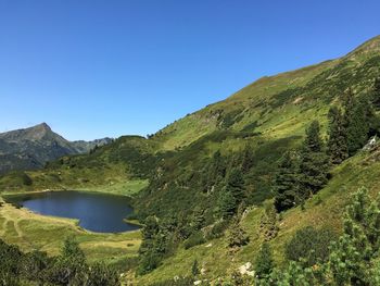 Scenic view of lake and mountains against clear blue sky