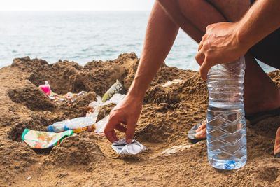 Low section of man picking garbage at beach