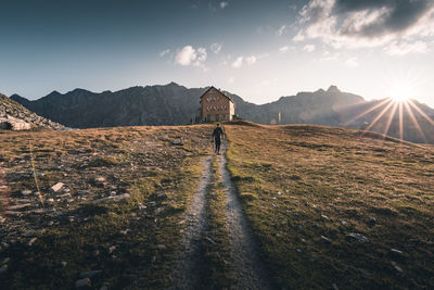 Rear view of man standing on mountain against sky