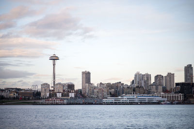 View of city at waterfront against cloudy sky