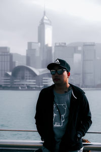 Man wearing sunglasses standing against cityscape