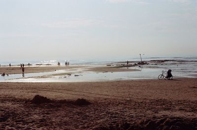 People at beach against sky