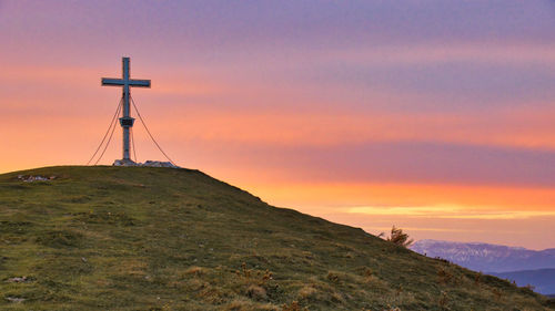 Cross on land against sky during sunset