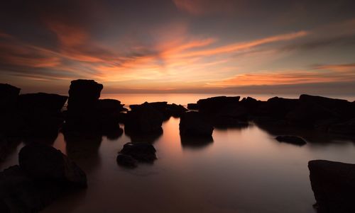 Silhouette rock formations against sky during sunset