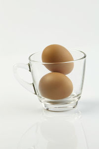 Close-up of eggs in coffee cup on white background