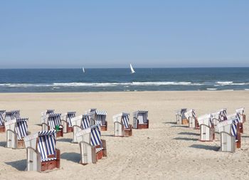 Deck chairs on beach against clear sky