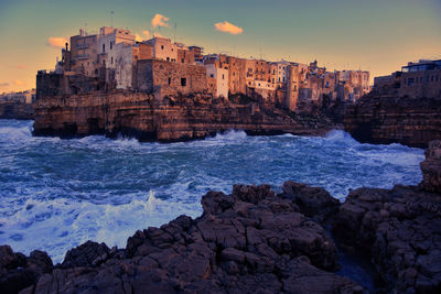 Panoramic view of sea and buildings against sky during sunset