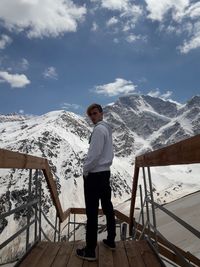 Portrait of young man standing on observation point against sky during winter