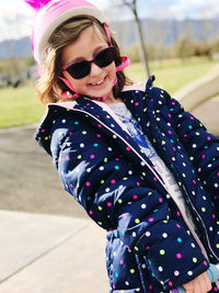 Portrait of girl wearing sunglasses while riding push scooter on road