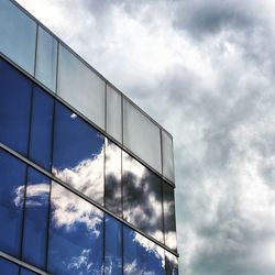 Low angle view of glass building against sky