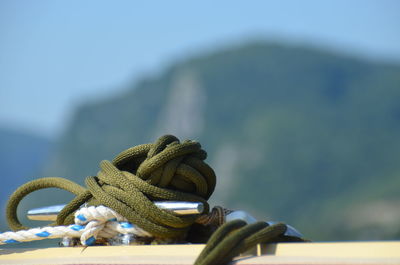 Close-up of rope tied on metal against sky