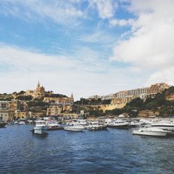 Sailboats moored in harbor against buildings in city