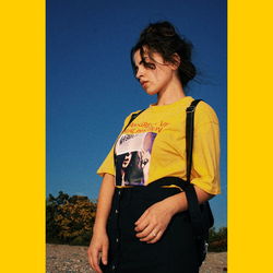 Woman standing against yellow wall against clear blue sky