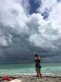 Full length of woman standing at beach against sky