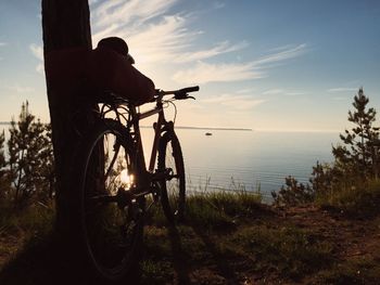 Silhouette of tree by sea against sky