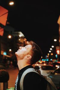 Portrait of man against illuminated city at night