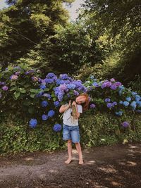 Full length of boy standing against blooming flowering plants