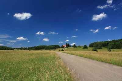 Road amidst field against sky