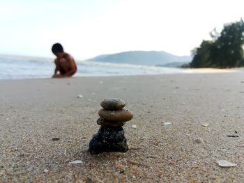 Stack of pebbles on beach against sky