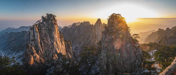 Panoramic view of rocks and mountains against sky during sunset