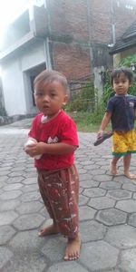 Cute boy looking down while standing on footpath