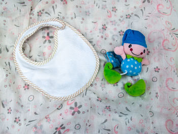 High angle view of baby bib and toy on fabric