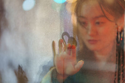 Sad korean girl draw heart shape on misty window surface unhappy because of breakup with boyfriend