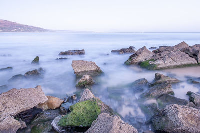 Scenic view of rocks in sea against sky