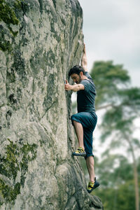 Rear view of young woman climbing on rock