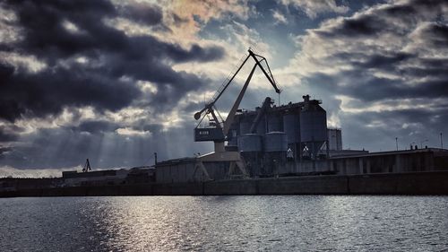 Cranes at commercial dock against sky