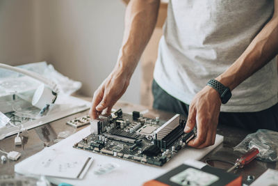 Tech tinkerer, amidst array of electronic parts, craftsman engages in delicate, computer maintenance