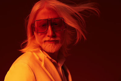 Portrait of young woman wearing sunglasses against black background