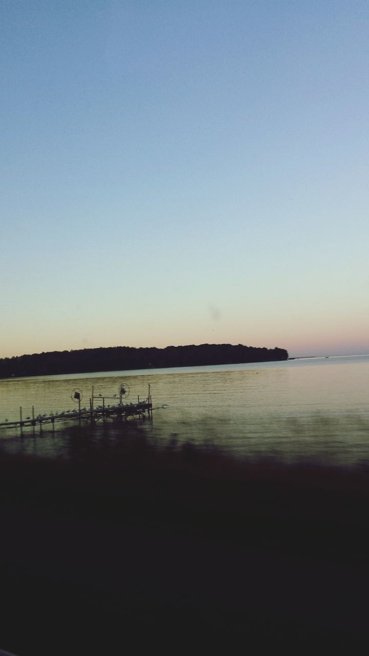 clear sky, water, copy space, sea, tranquil scene, sunset, tranquility, scenics, beauty in nature, beach, silhouette, horizon over water, nature, idyllic, shore, outdoors, incidental people, calm, blue, remote