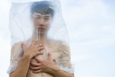 Midsection of couple holding hands against sky