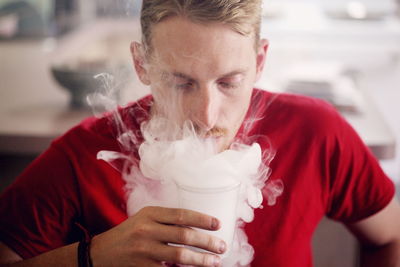 Man exhaling smoke in glass