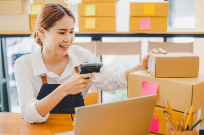 Young woman using phone while sitting on table