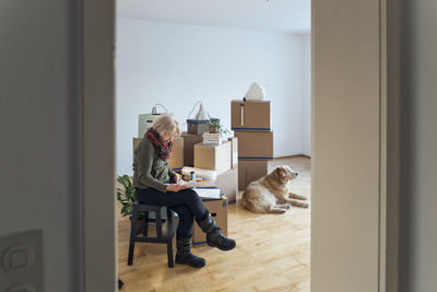 Senior woman looking at papers surrounded by cardboard boxes in an empty room