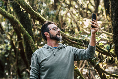 Low angle view of man doing selfie in forest