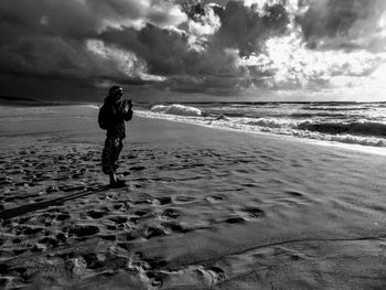 Full length of man standing on beach against sky