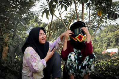 Happy friends standing by tree against plants