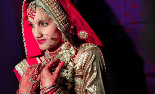 Close-up of bride wearing traditional clothing looking away while standing indoors