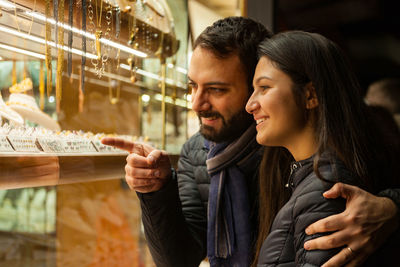 Smiling couple looking at jewelry in store through window