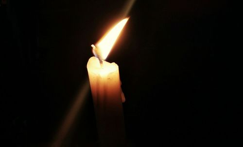 Close-up of lit candle in darkroom