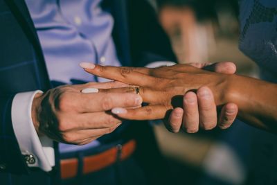 Midsection of man putting ring in woman finger