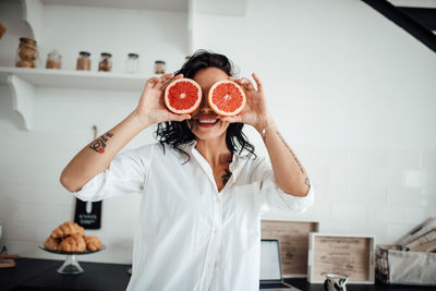 Smiling woman holding blood orange at kitchen
