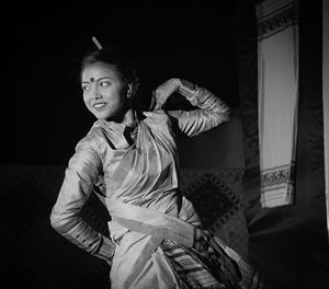 Smiling mid adult woman wearing traditional clothing dancing in room