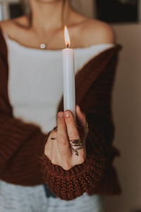 Midsection of woman holding candle at home