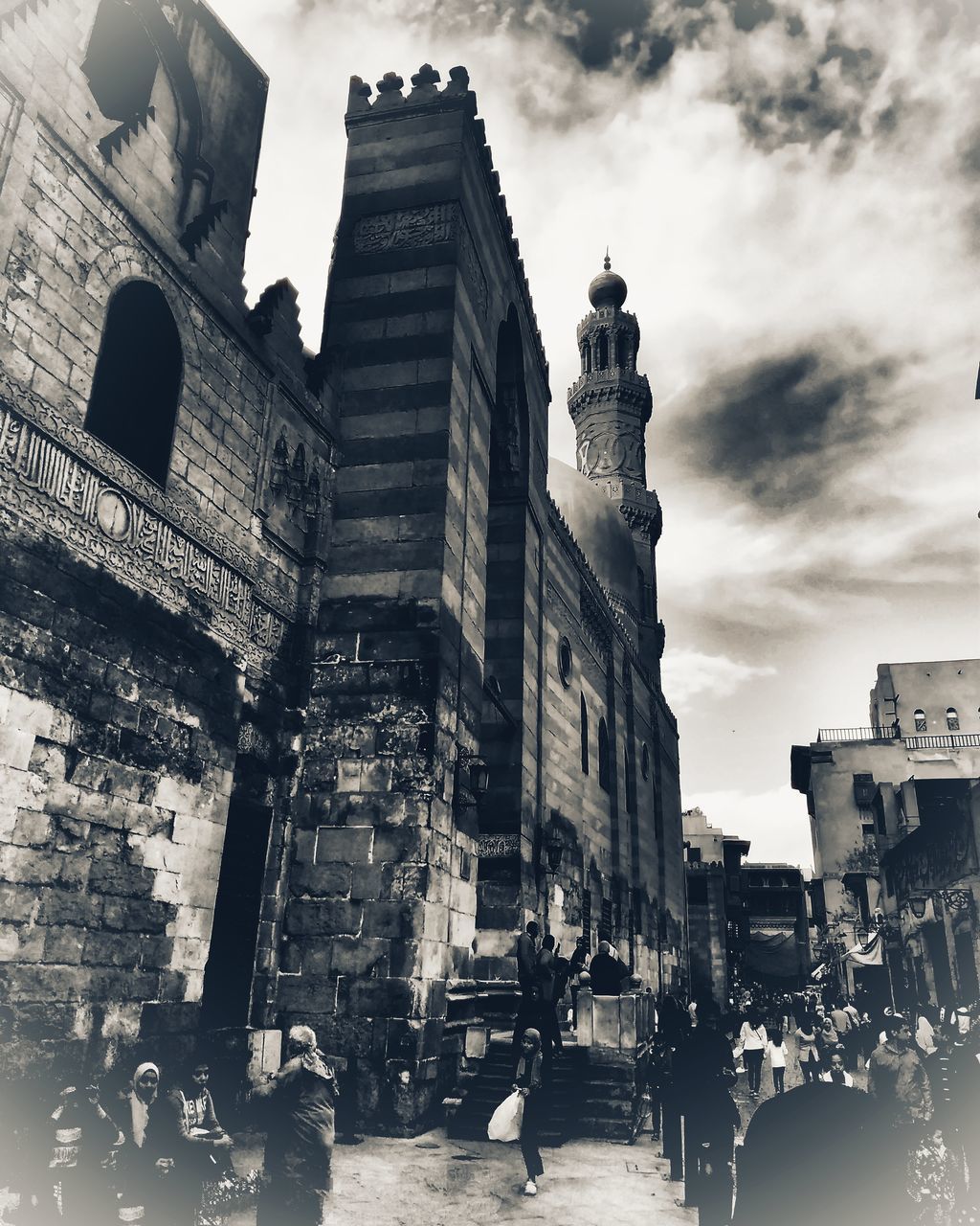 PEOPLE ON STREET BY BUILDINGS IN CITY AGAINST SKY