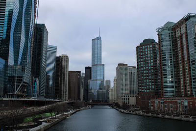 River amidst buildings in city against sky