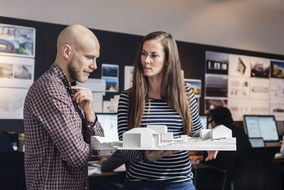 Business people discussing over model in office